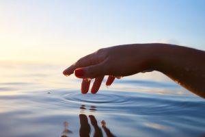 Spiegelung einer Hand im Wasser